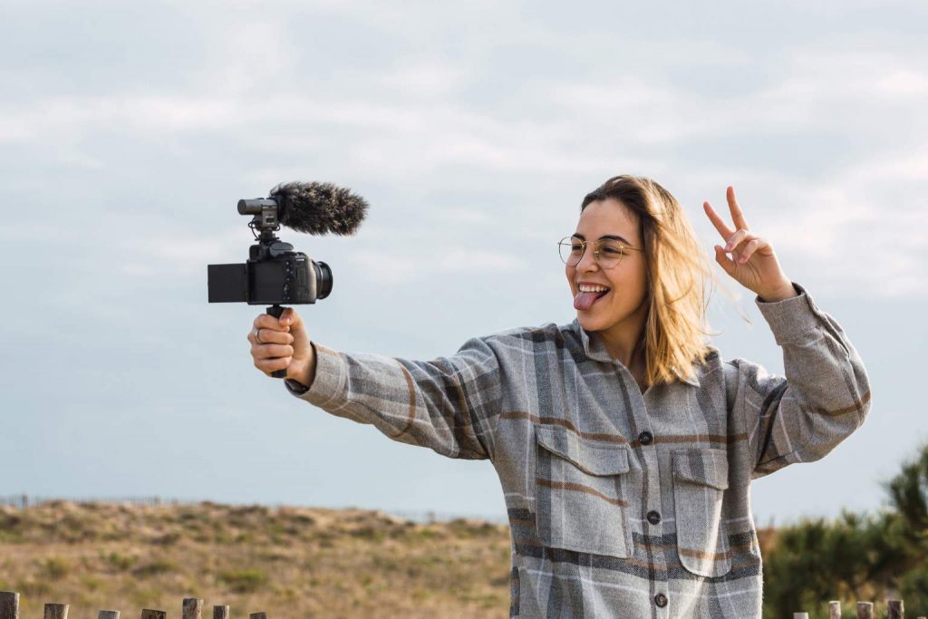 Vlogger holding a camera while filming, featured in The Most Exciting Camera Releases of 2025