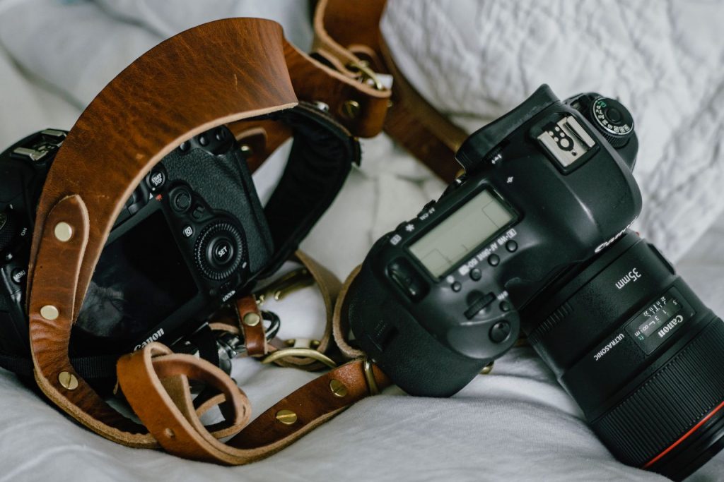 Two DSLR cameras with leather straps resting on a soft surface, highlighting Why Smart Creators Are Listing Before Everyone Else to capture pre-rush attention.