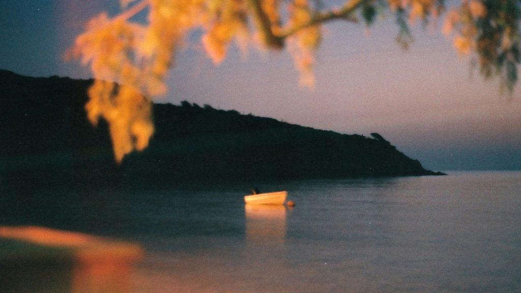 Soft, atmospheric film photograph of a small boat on calm water at dusk, reflecting the emotional appeal behind Film Ricoh GR Actually Possible.