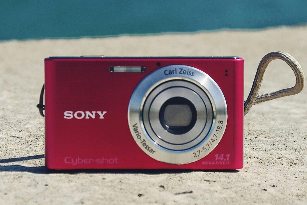 Red Sony Cyber-shot digicam on sand — why are digicams popular again in 2025