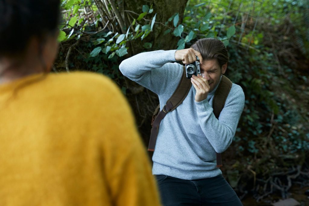 A photographer using a film camera to shoot a portrait subject outdoors — casting photography requires choosing the right person before the shutter clicks