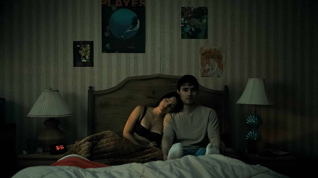 Nikki rests on Bear's shoulder in a dimly lit bedroom in a quiet two-shot from "Obsession."