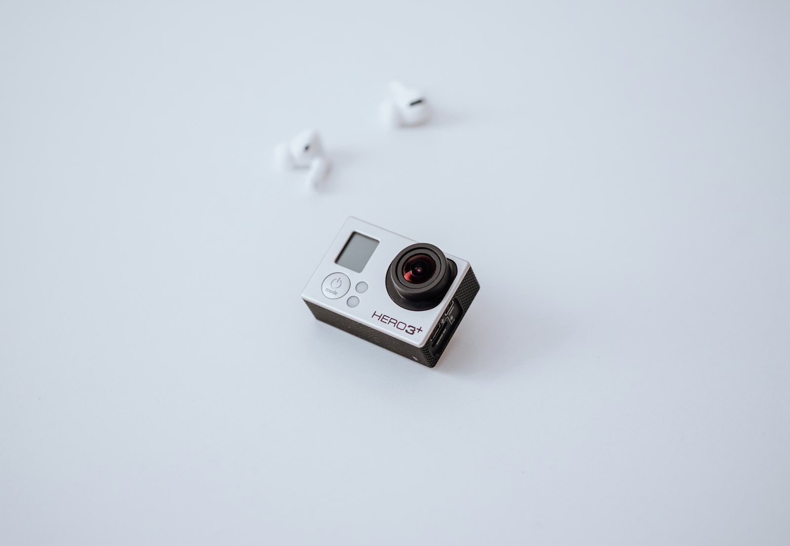 action camera and wireless earbuds arranged on a white surface