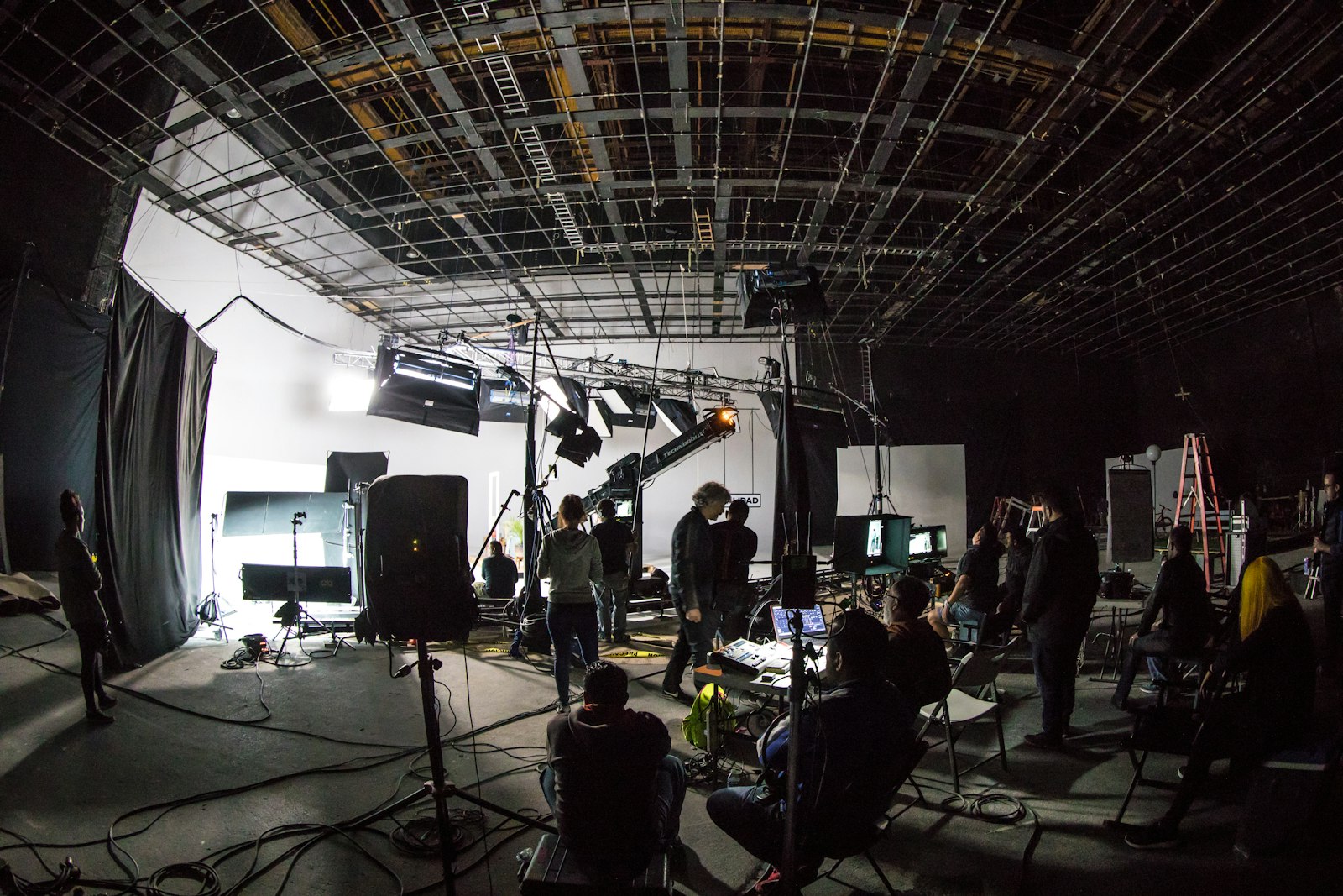 film crew working on a soundstage surrounded by lighting equipment, stands, and cameras