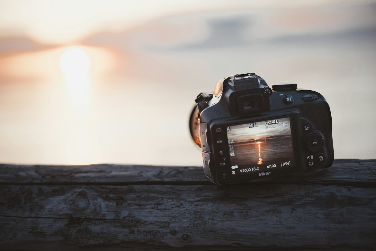 digital camera resting on a wooden surface overlooking water at sunset