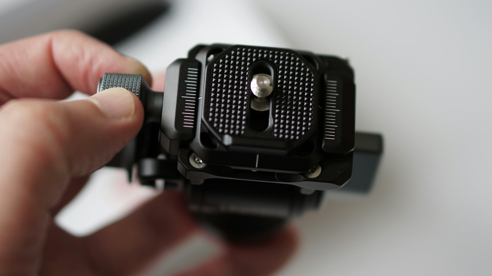 person's hand holding a tripod ball head quick-release plate assembly